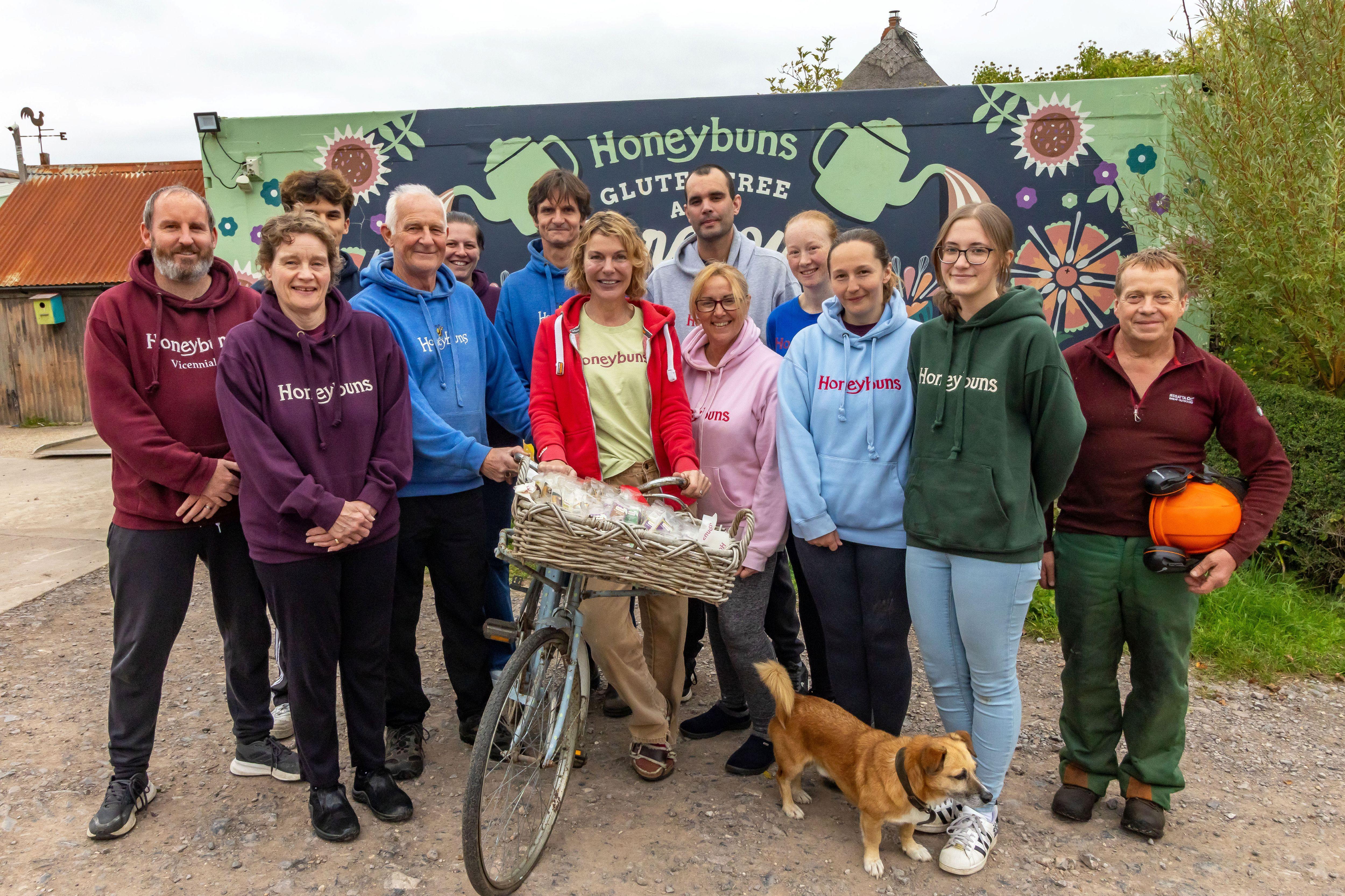 A group of people standing in front of a wall mural that says Honeybuns Bakery