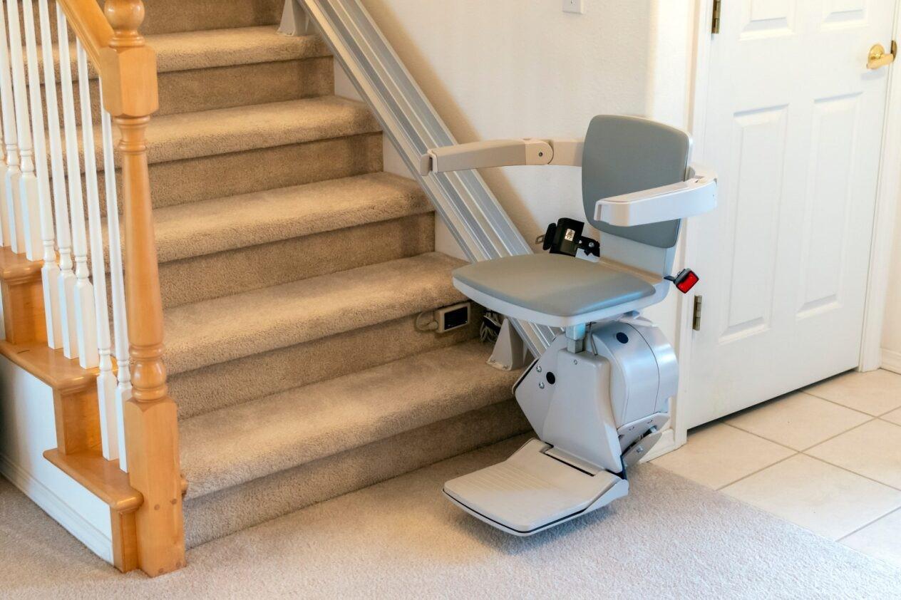 Image of a stair lift, it is parked at the bottom of stairs and is not in use