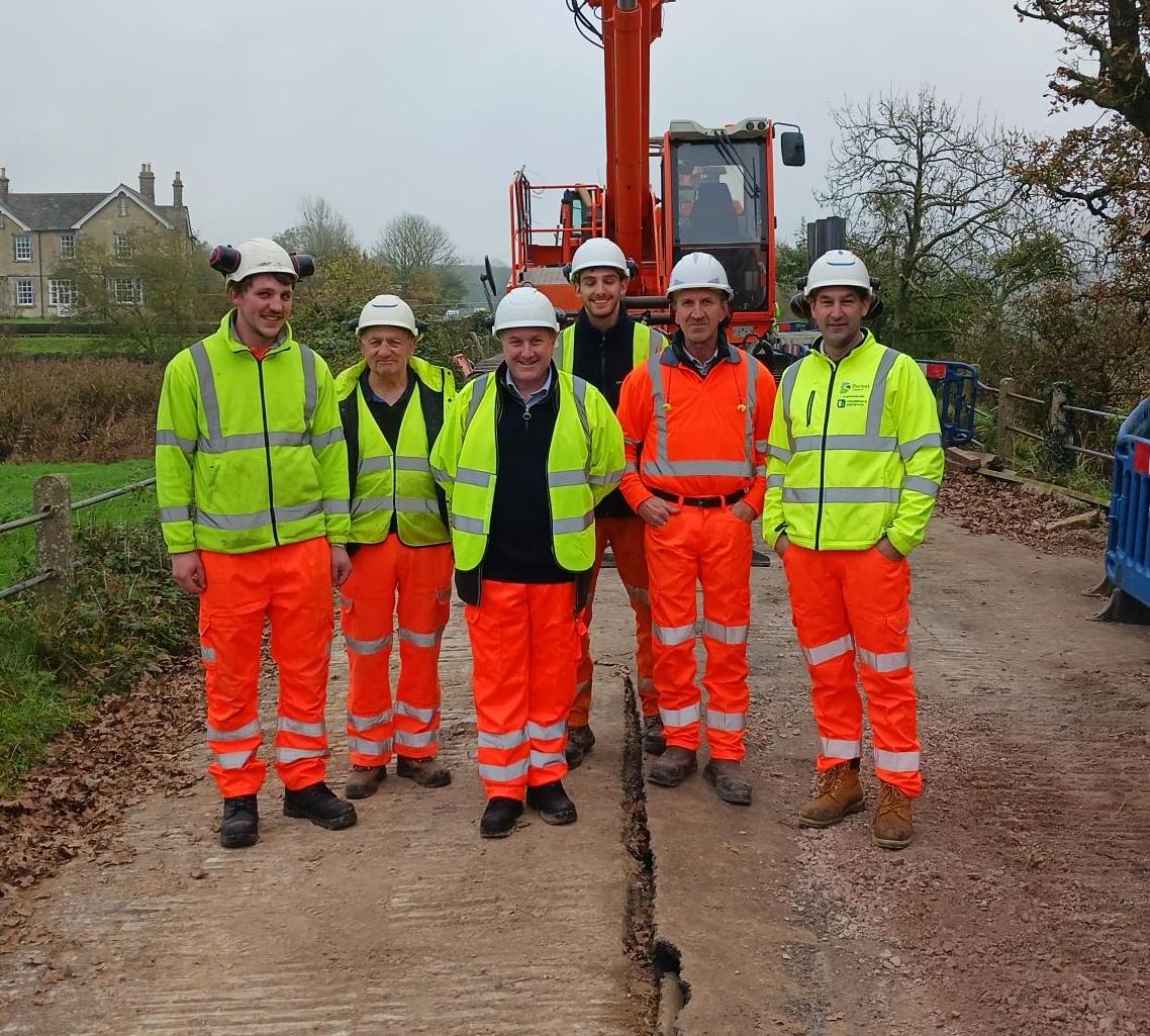 People wearing yellow jackets and orange trousers standing in front of piling equipment