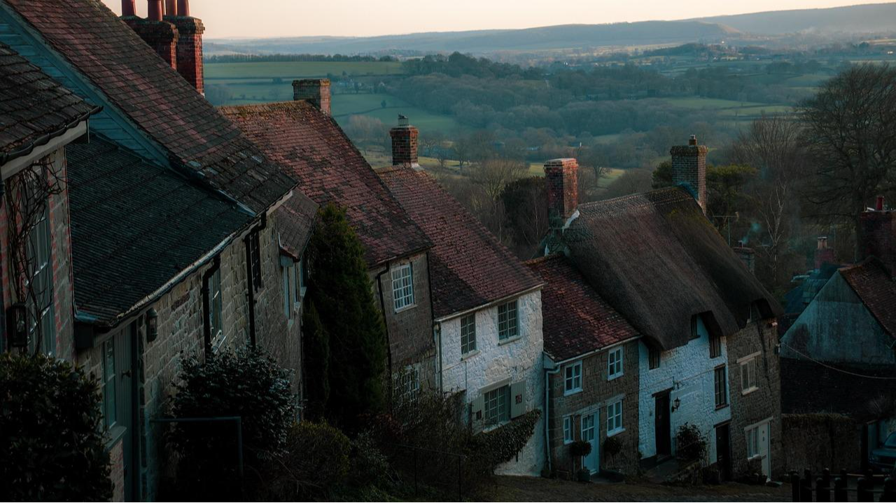Shaftesbury&#39;s Gold Hill. A steep cobbled street lined with pretty cottages some of which have thatched roofs. Other roofs are tiled. This street featured in the famous Hovis advert.