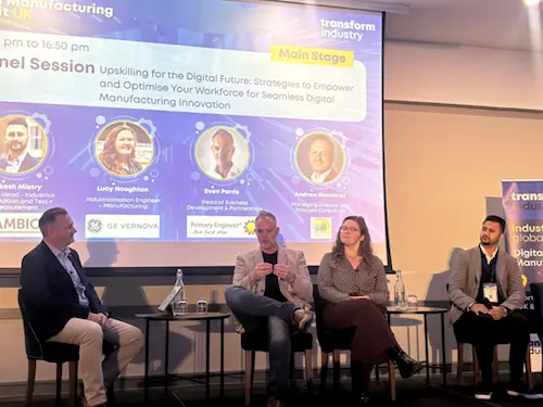 Panel discussion taking place on a conference stage, with four speakers seated in front of a large screen displaying event branding and session details about upskilling for the digital future.
