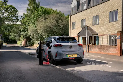Electric car parked on a residential street while plugged into a kerbside charging unit.
