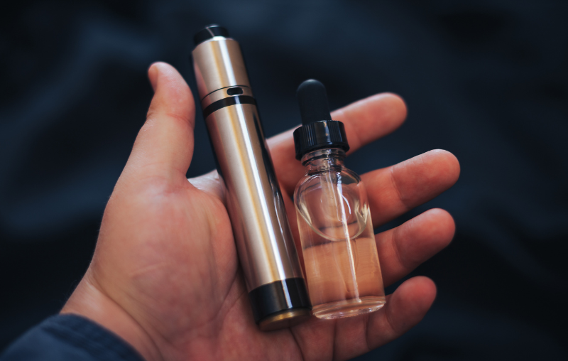Someone holding a vape kit in the palm of their hand