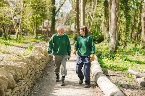 Two people walking together along a woodland path.