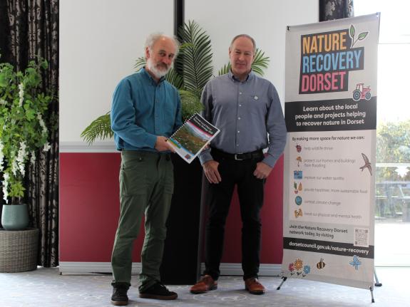 Two men standing in front of a sign that says Dorset Local Nature Recovery Strategy